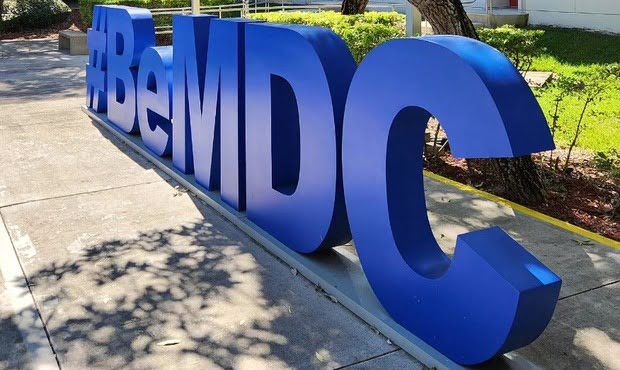 Group of SGA students pose next to the Homestead Campus floor insignia
