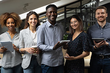 Smiling multiracial business team standing together looking at camera in office