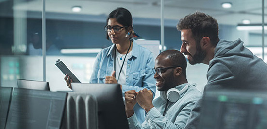 Cybersecurity workers collaborating together in front of many computers