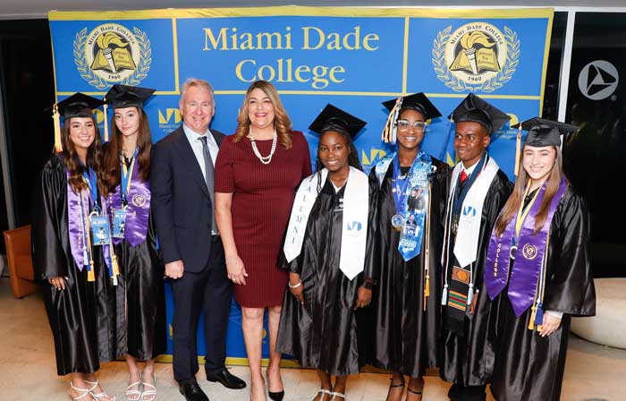a group of graduating student in cap and gown, with college officials.